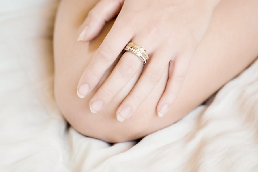 Left hand resting on knee Tricolour Triple Spinner Ring with Sparkling Texture on middle finger